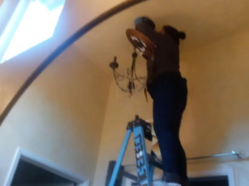 Electrician installing a chandelier in a Grass Lake residence